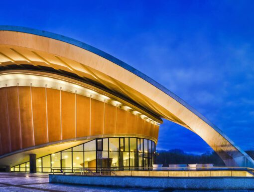 A large building with a curved roof at night.