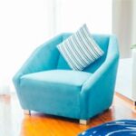 A blue chair with striped pillow on the arm.