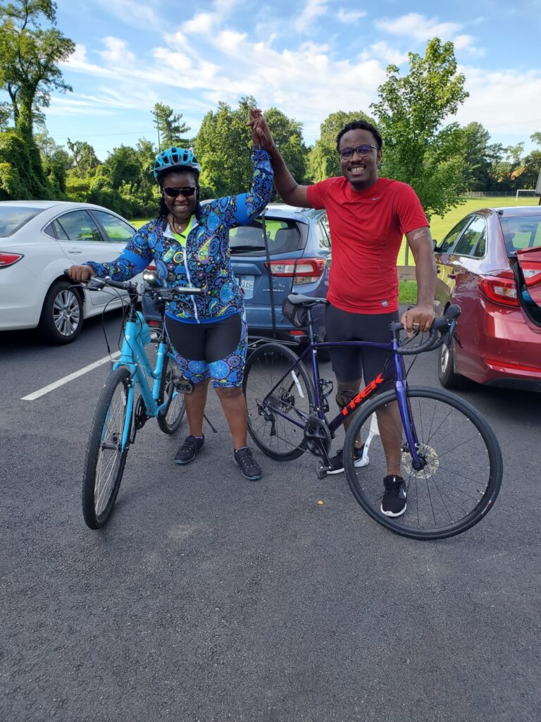 Two people standing in a parking lot with bikes.